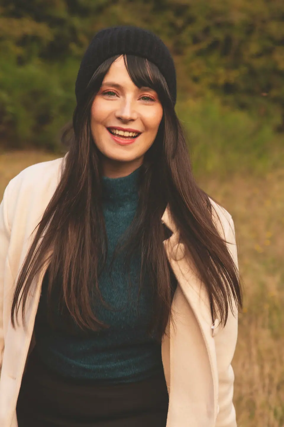 Morgane Muller souriante, en manteau clair, dans une prairie en fin de journée